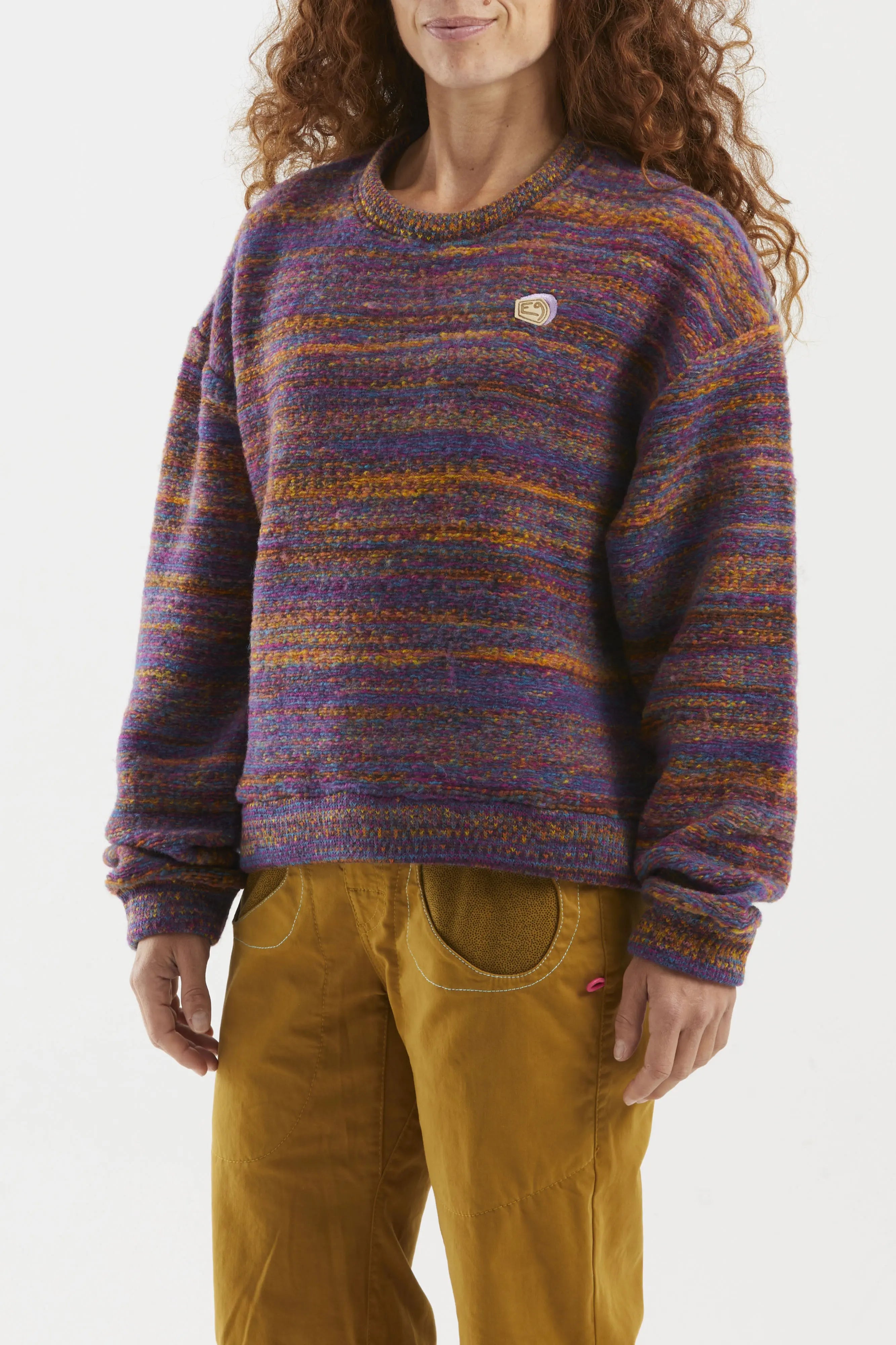 Person wearing a multicolored wool sweater and mustard pants on a white background