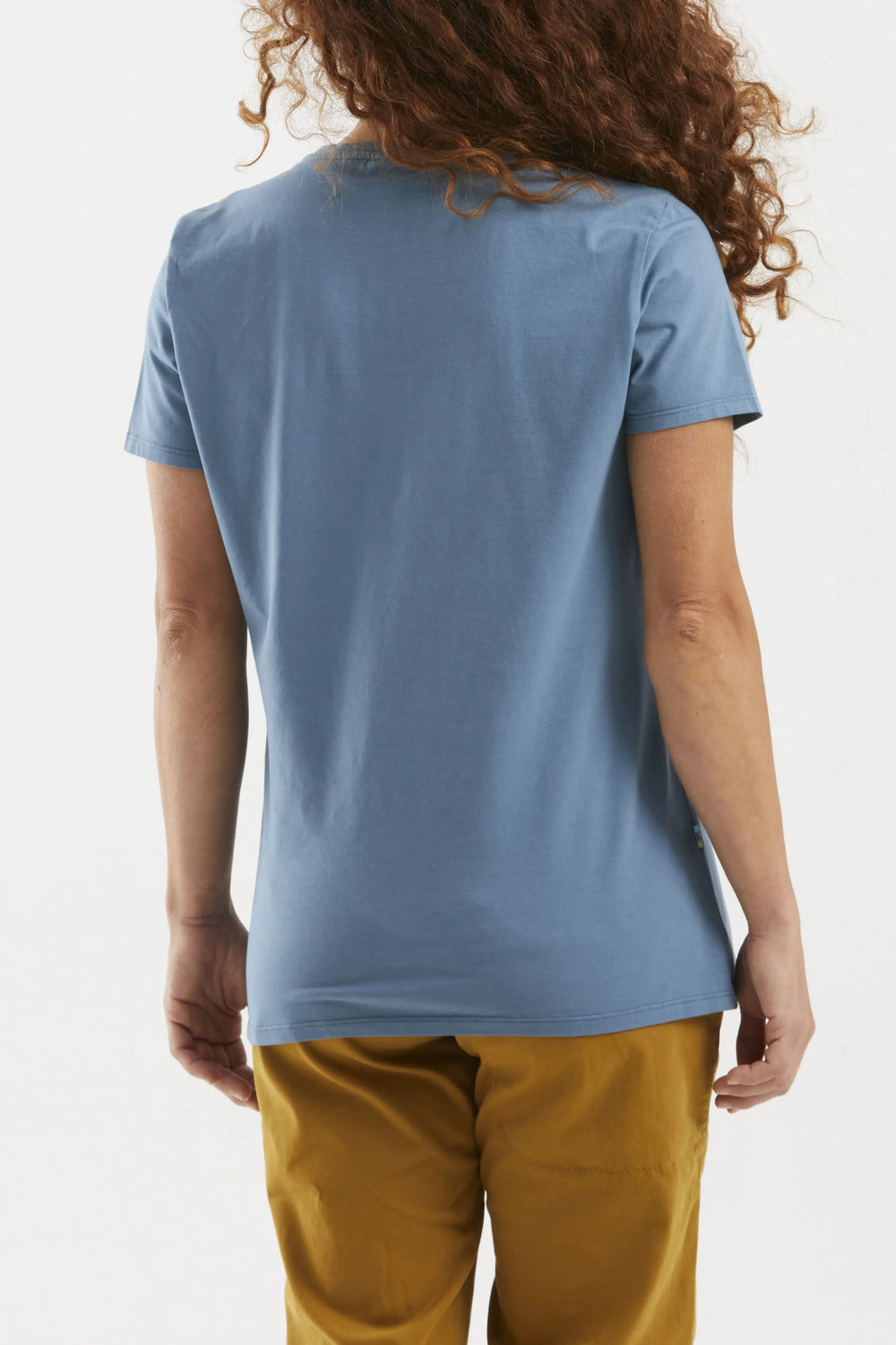 Woman wearing a blue t-shirt and mustard yellow pants on a white background