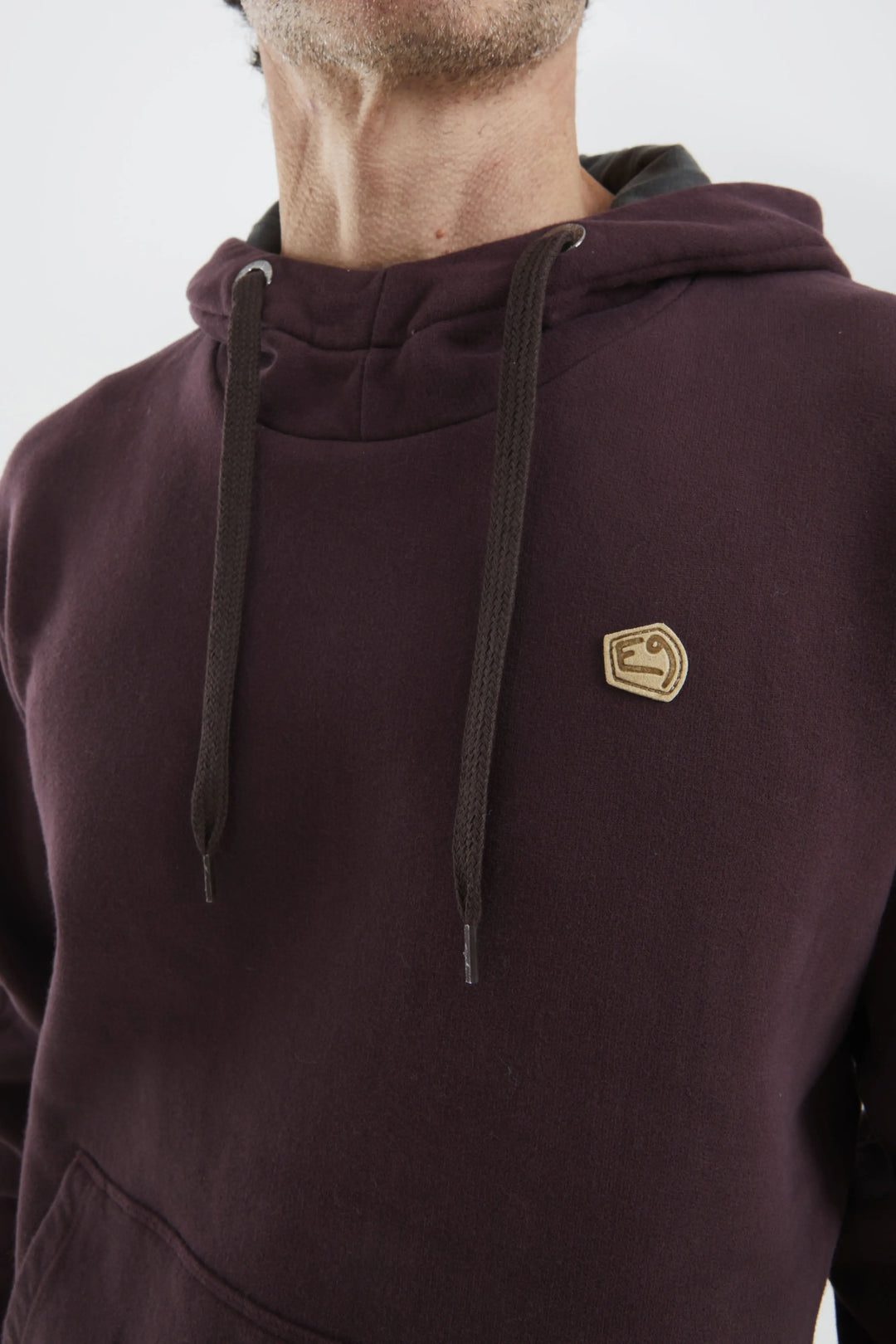Close-up of a maroon hoodie with a e9 logo on a white background